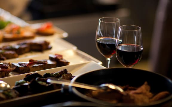 two glasses of red wine next to a plate of food