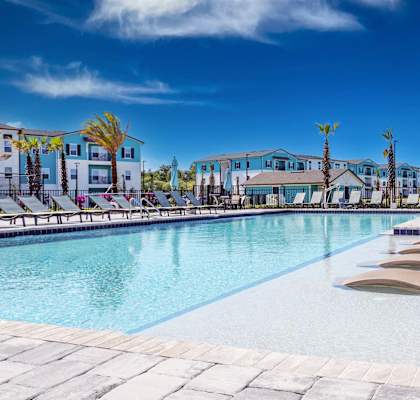 a swimming pool with chaise lounge chairs and buildings in the background