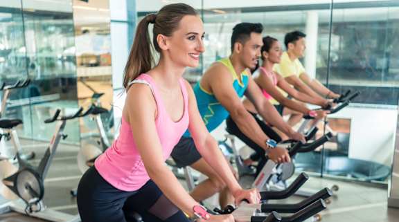 A group of people are exercising on stationary bikes in a gym.