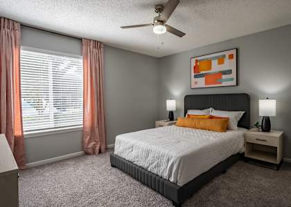 A bedroom with a bed, nightstand, and window with curtains. at Spalding Vue, Peachtree Corners