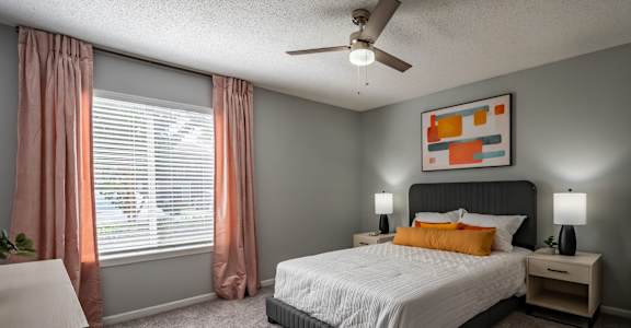 A bedroom with a bed, nightstand, and window with curtains.