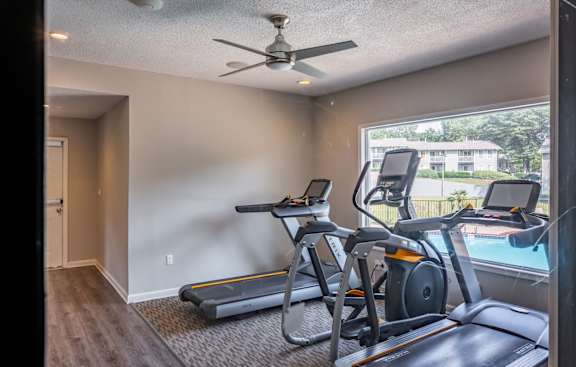 A home gym with a treadmill, elliptical trainer, and stationary bike.