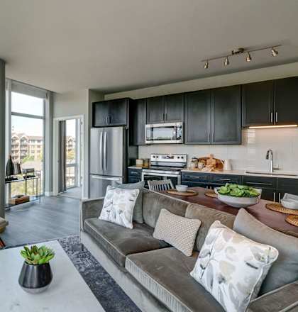 A modern living room with a grey couch and a wooden table.