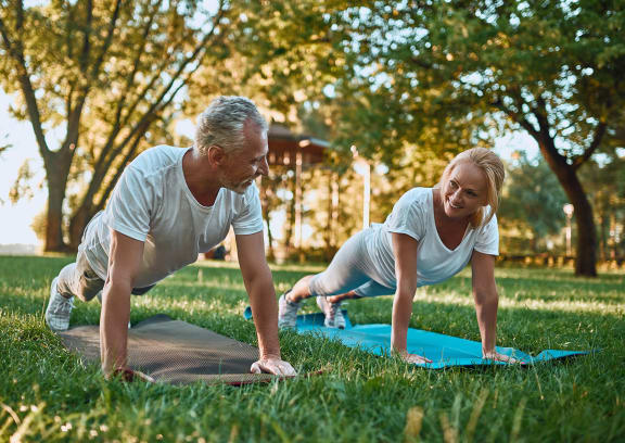 a man and a woman doing yoga in the park