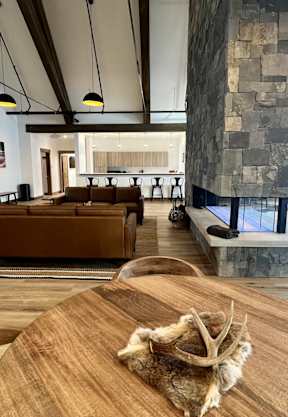 A wooden table with a cloth on it is in the foreground of an indoor space with a stone wall and wooden floors at Silverbrook Apartments Apartments, Kalispell