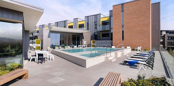 A modern building with a pool and lounge chairs.