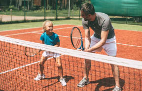 Father Playing Tennis Next to Daughter