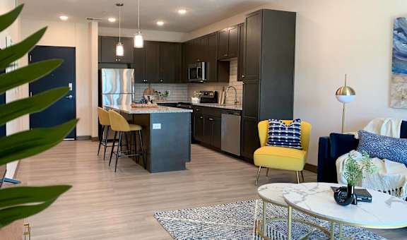 the view of the kitchen with dark cabinets from the corner of the living room