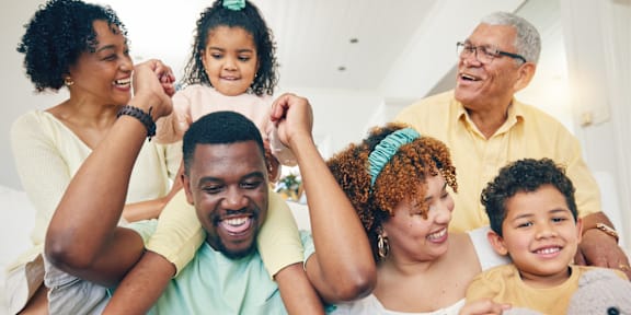 A family of five is sitting together, smiling and enjoying each other's company.
