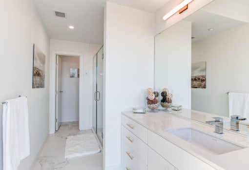 a white bathroom with a sink and a shower