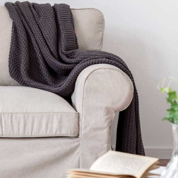 a grey couch with a black blanket on top of it