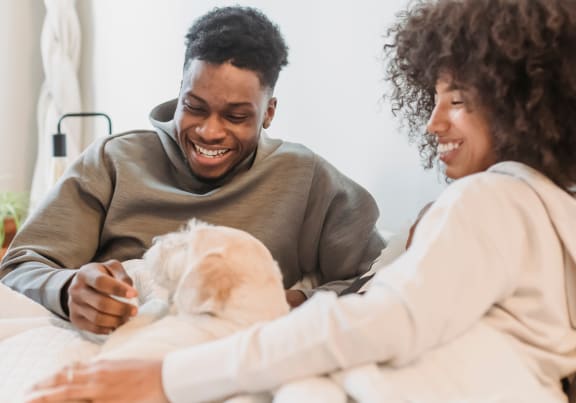 a man and woman in bed holding a baby dog
