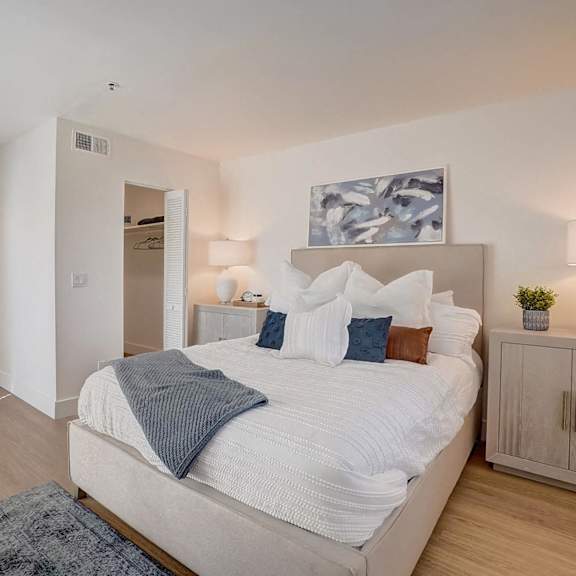 A bedroom with a large bed, a nightstand, and a painting on the wall.
