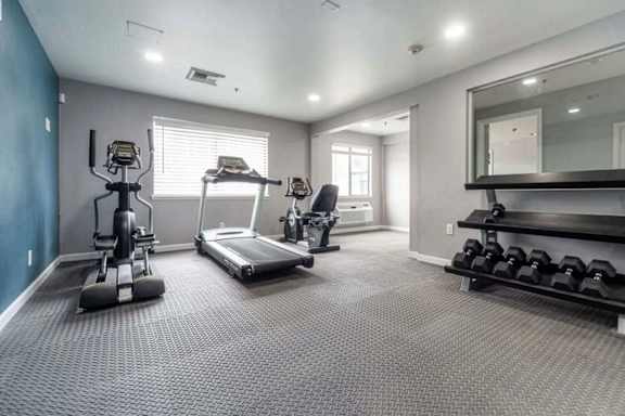 A spacious home gym with a variety of equipment including a treadmill, weights, and a bench press.