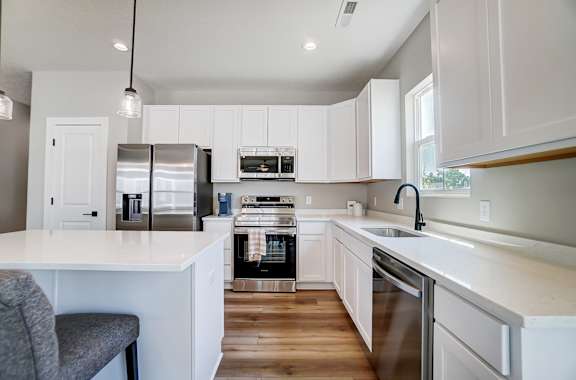 A modern kitchen with white cabinets and stainless steel appliances.