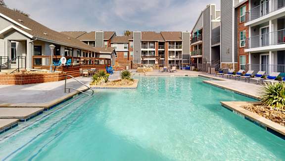 A swimming pool in a residential area with apartment buildings in the background.