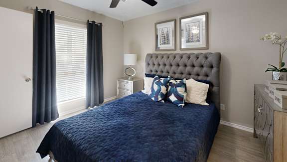 A bedroom with a bed, nightstand, and a ceiling fan.
