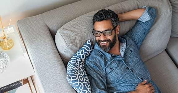 a man laying on a couch with his head on a pillow