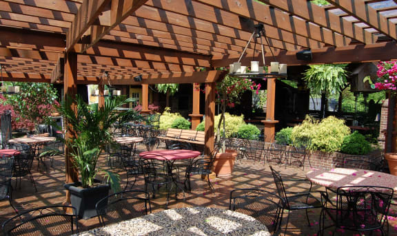 a patio with tables and chairs and a wooden pergola