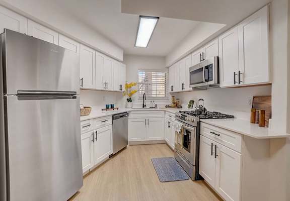 A modern kitchen with white cabinets and stainless steel appliances.