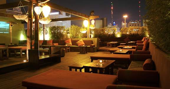 A patio with tables and chairs is lit up at night.
