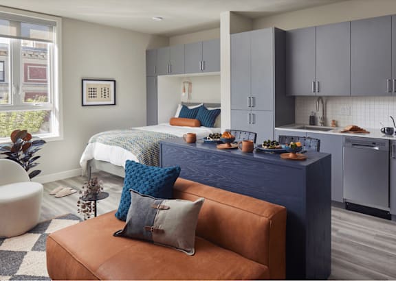 a studio apartment with a bed and a kitchen and a couch