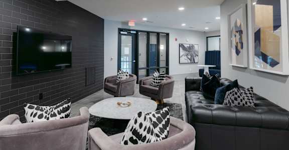 A living room with a black couch, a grey armchair, and a coffee table at Caldwell, Houston, TX, 77084