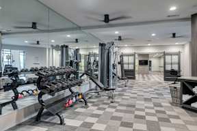 A gym with a variety of equipment including dumbbells at Caldwell, Houston, TX, 77084