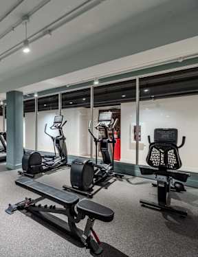 A gym with a variety of equipment including treadmills, weights, and exercise machines.