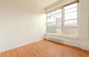 A room with a window and wooden flooring.