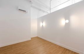 A room with wooden flooring and two wall lights.