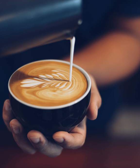 A person is pouring milk into a cup of coffee.