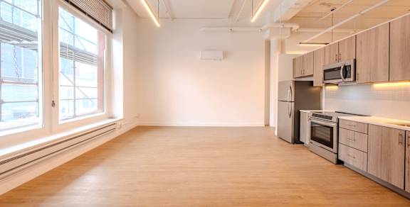 A spacious kitchen with wooden floors and stainless steel appliances.