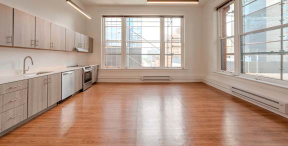 A large empty room with wooden floors and a window overlooking a cityscape.