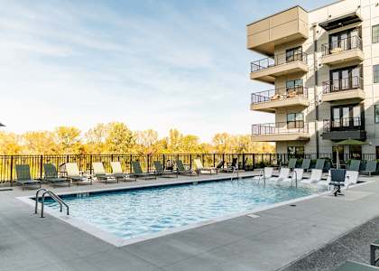 A swimming pool is surrounded by lounge chairs and apartment buildings at Harbor Side at Conwood Flats Apartments, Memphis, TN, 38107
