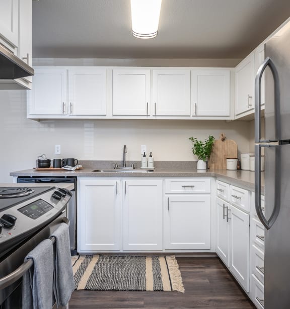 a kitchen with white cabinets and stainless steel appliances at Sundial Apartments, Oregon