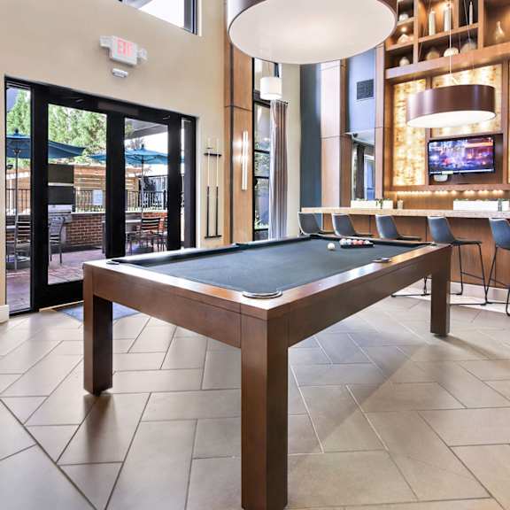 A pool table in a room with a television and a bar.