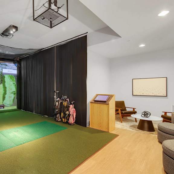 A room with a green mat on the floor and a screen on the wall.