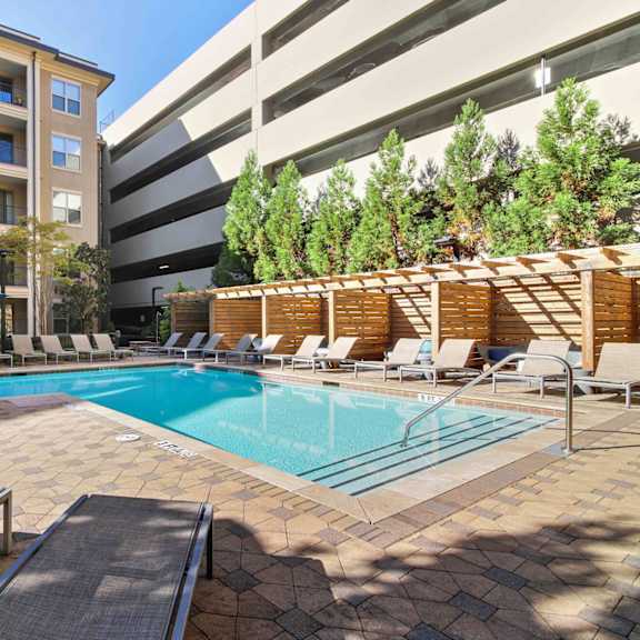A swimming pool surrounded by lounge chairs and trees.