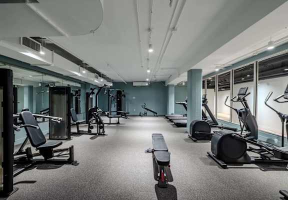 A gym with a variety of equipment including treadmills, weights, and exercise machines.