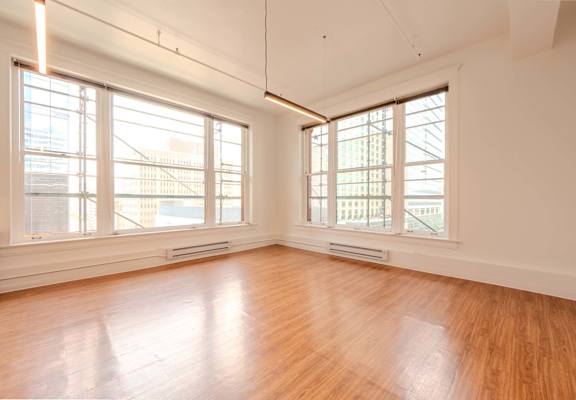 A room with wooden floors and large windows.