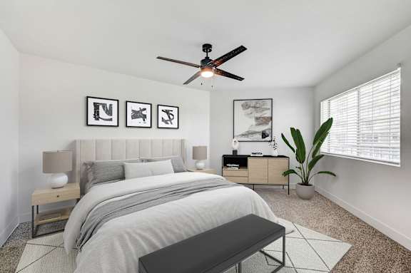 A bedroom with a bed, nightstand, and a plant.