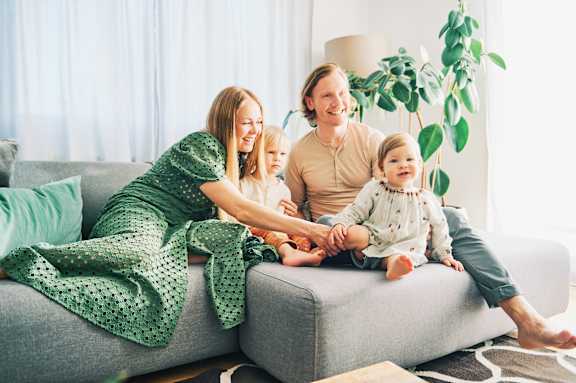 A family of four is sitting on a grey couch.