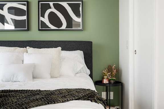 A bedroom with a white bed and two black and white artworks on the wall.