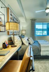 A bedroom with a bed, desk, and chair.at Elevation at the Village, Gilbert, 85295