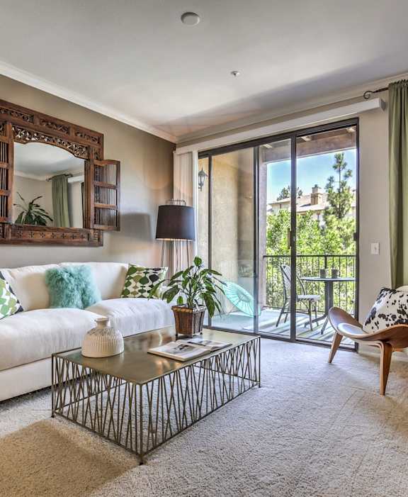 A living room with a white couch, a mirror, and a coffee table.