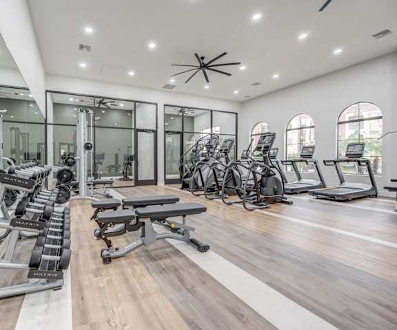 A gym with cardio machines, TVs, and weights. 