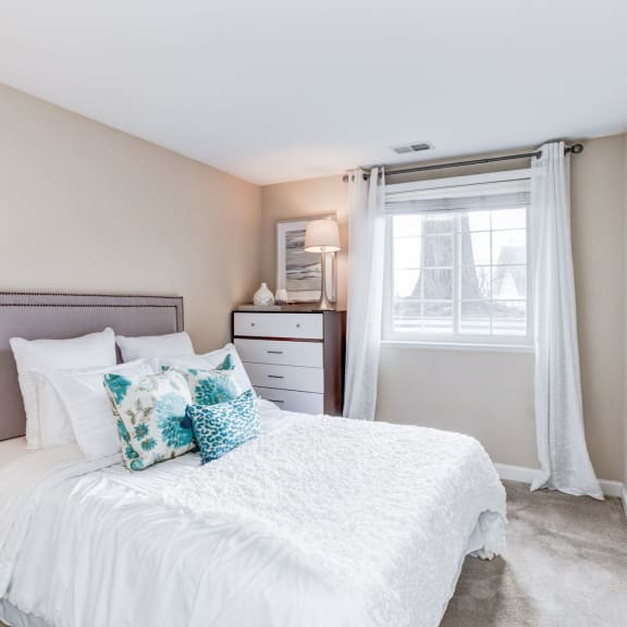 a bedroom with a bed and dresser in front of a window