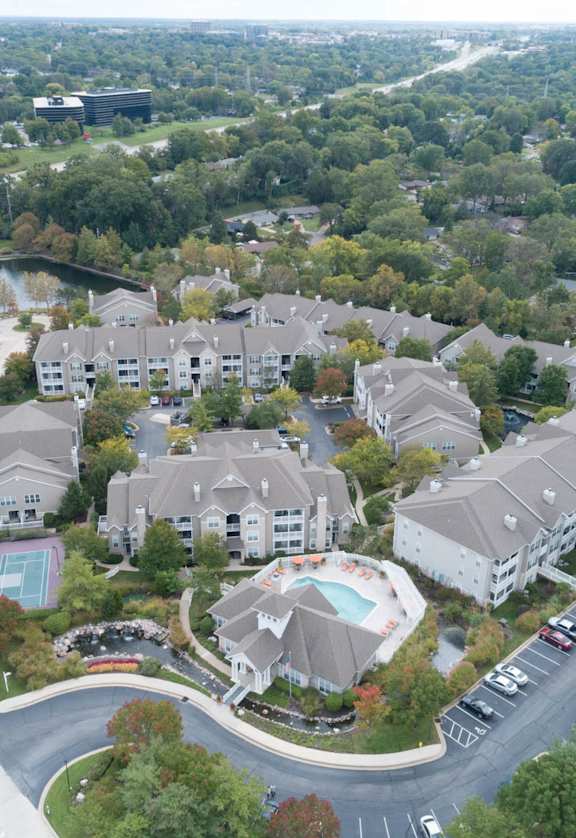 an aerial view of a large complex of houses with trees in the background