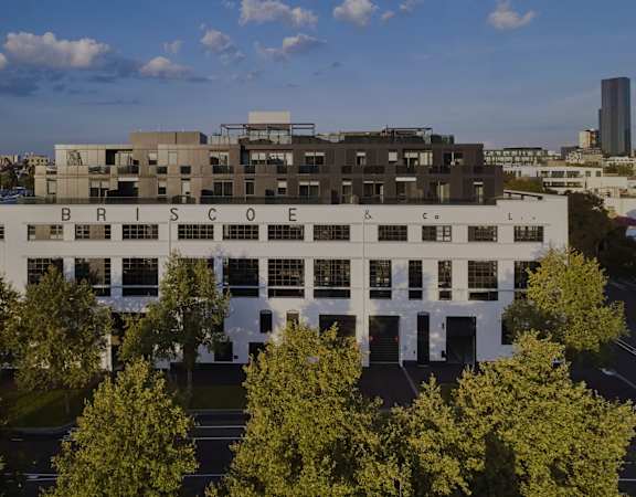 an aerial view of a white building with trees in front of it